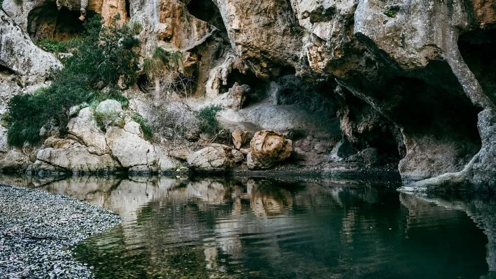 Grotte calcaire avec un bassin d'eau calme et des galets