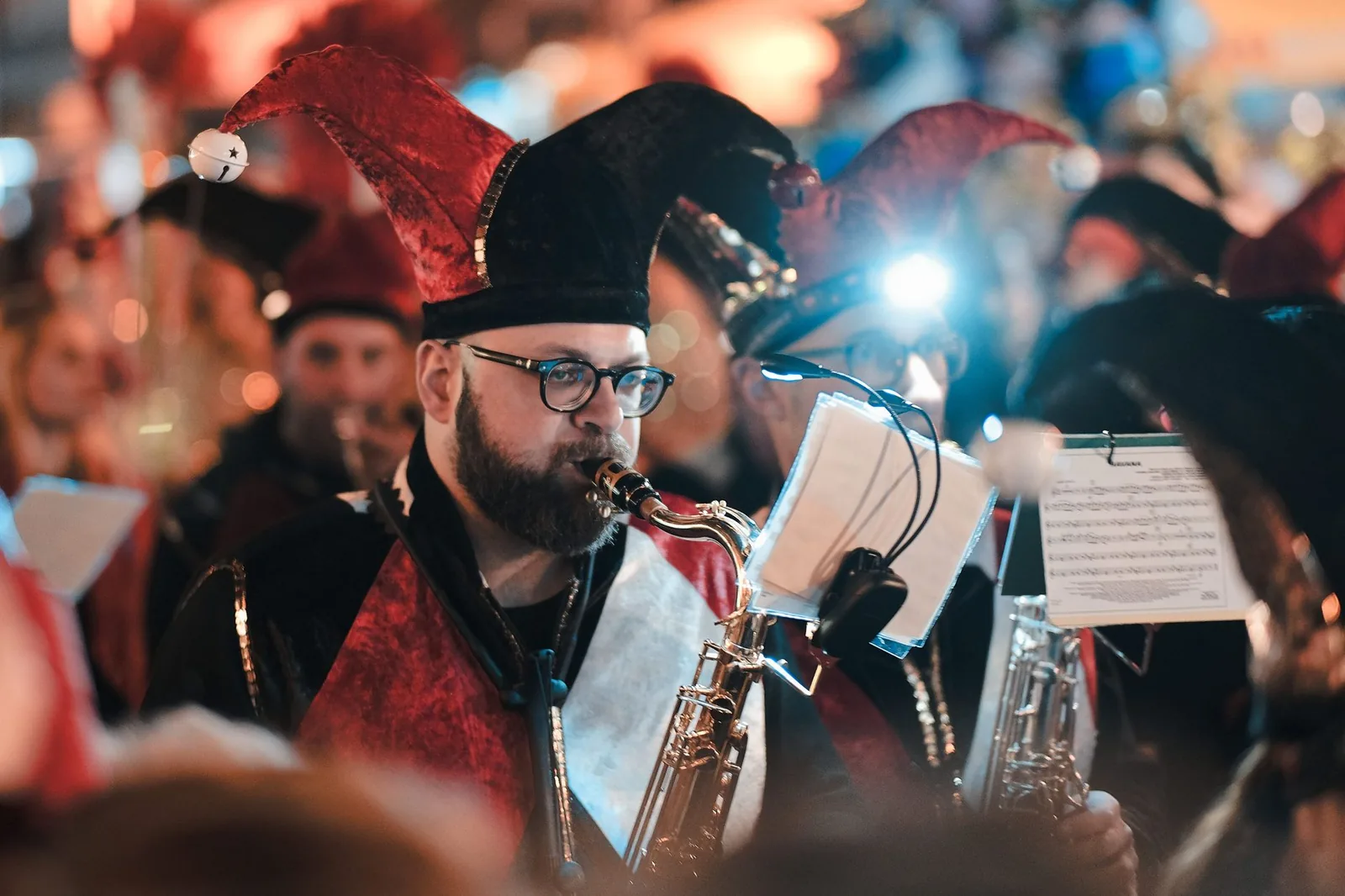 Musiciens de fanfare en costumes de bouffons jouant du saxophone pendant le carnaval de Limassol, de nuit