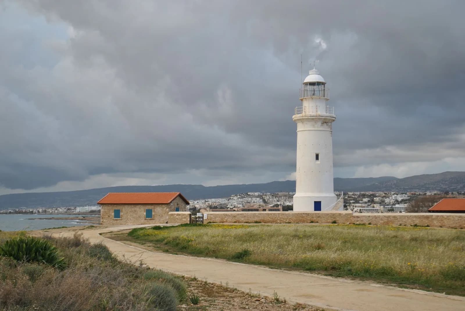 Phare blanc de Paphos, à Chypre, sous un ciel d'hiver chargé de gros nuages gris