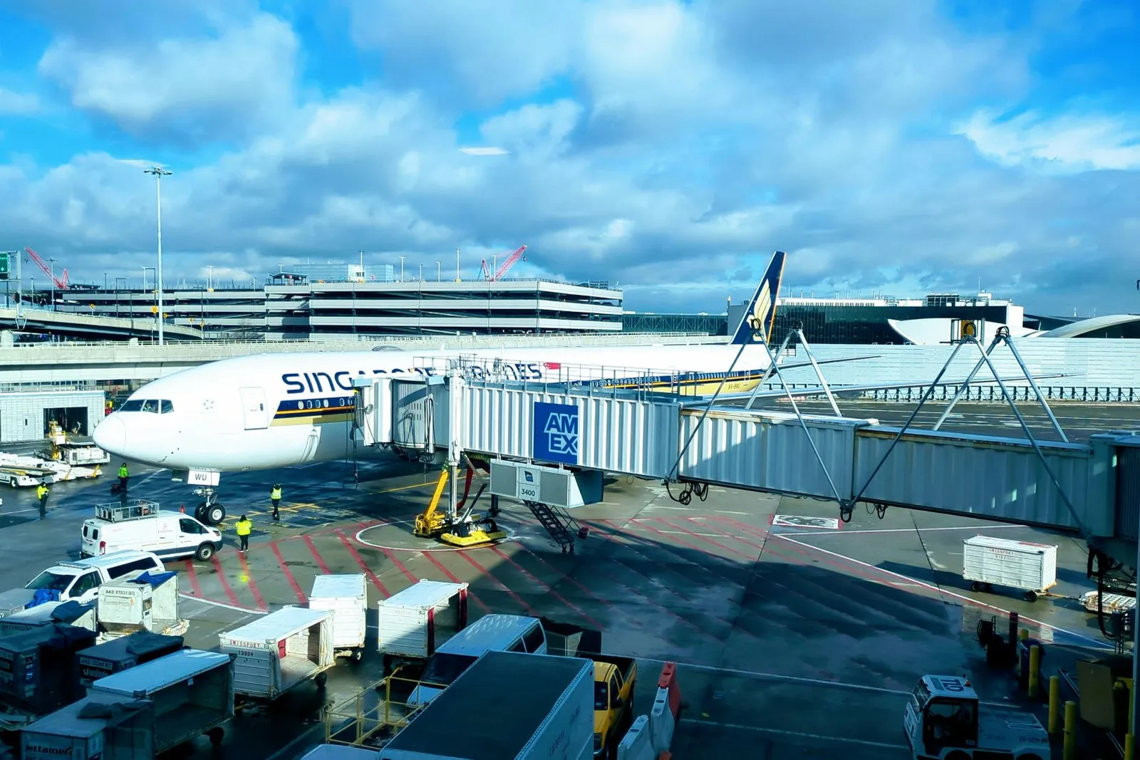 Avion de ligne stationné à la passerelle d'un aéroport, avec les véhicules d'assistance sur le tarmac
