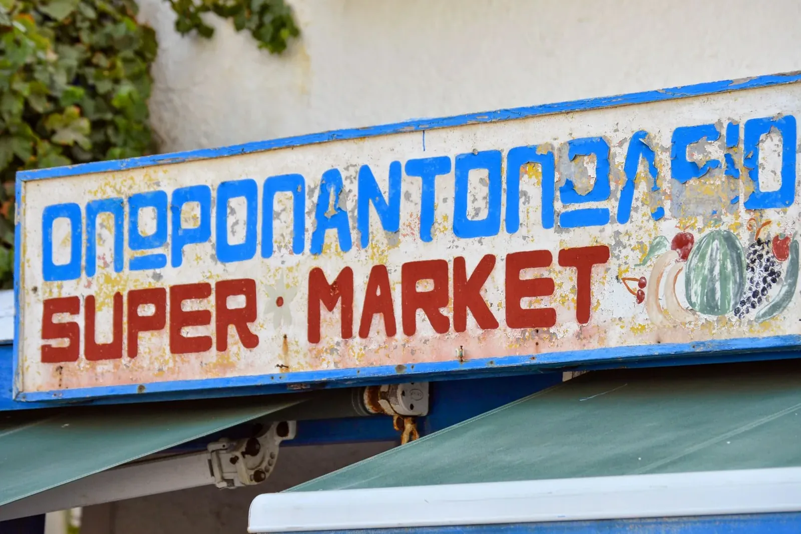 Enseigne peinte en lettres grecques, avec « SUPER MARKET » en lettres latines en dessous