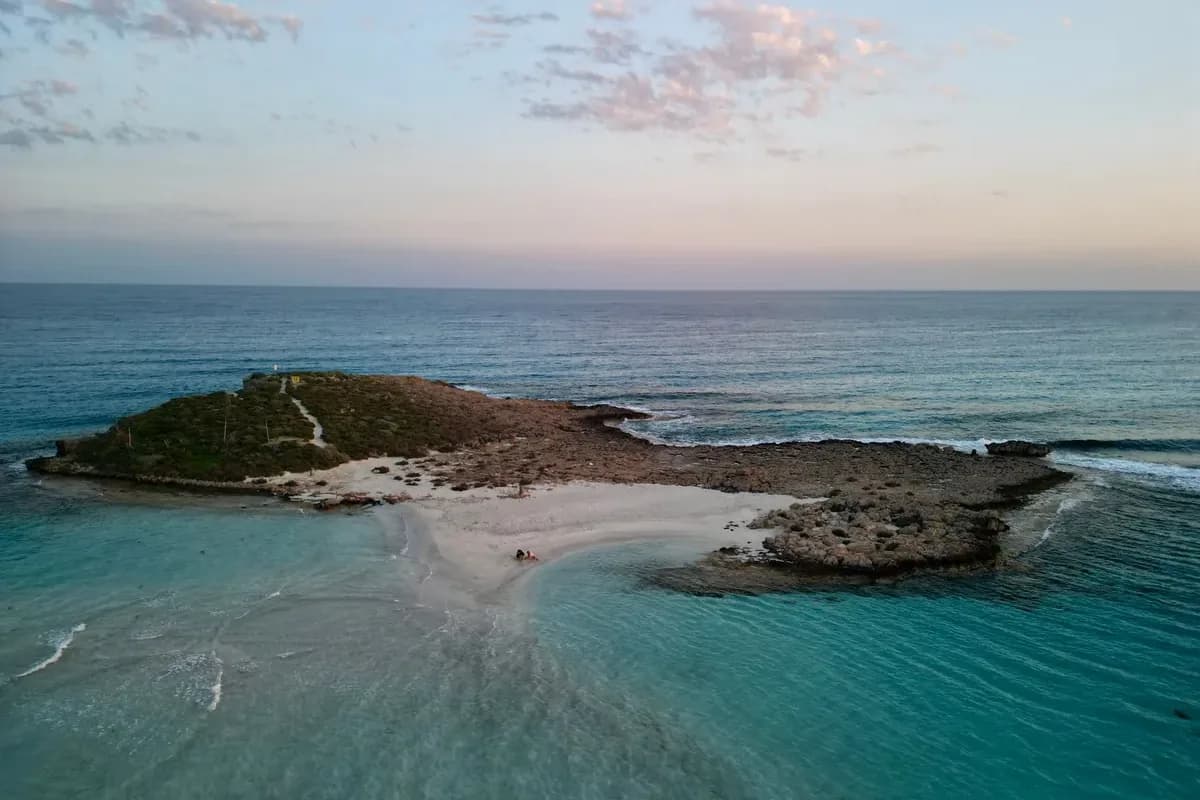 Banc de sable en eau peu profonde menant à l'îlot rocheux de Nissi Beach, à Ayia Napa, au crépuscule