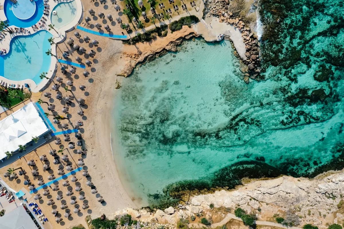Vue aérienne de rangées de parasols et de transats sur la plage d'un hôtel du front de mer d'Ayia Napa