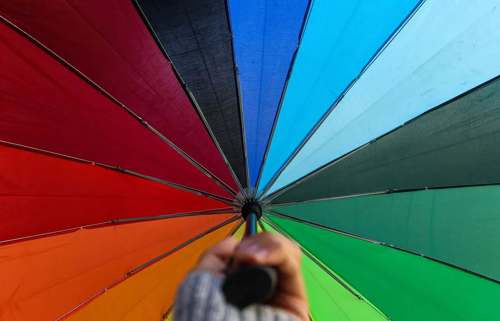 Main tenant un parapluie multicolore vu de dessous, symbole de protection et d'assurance