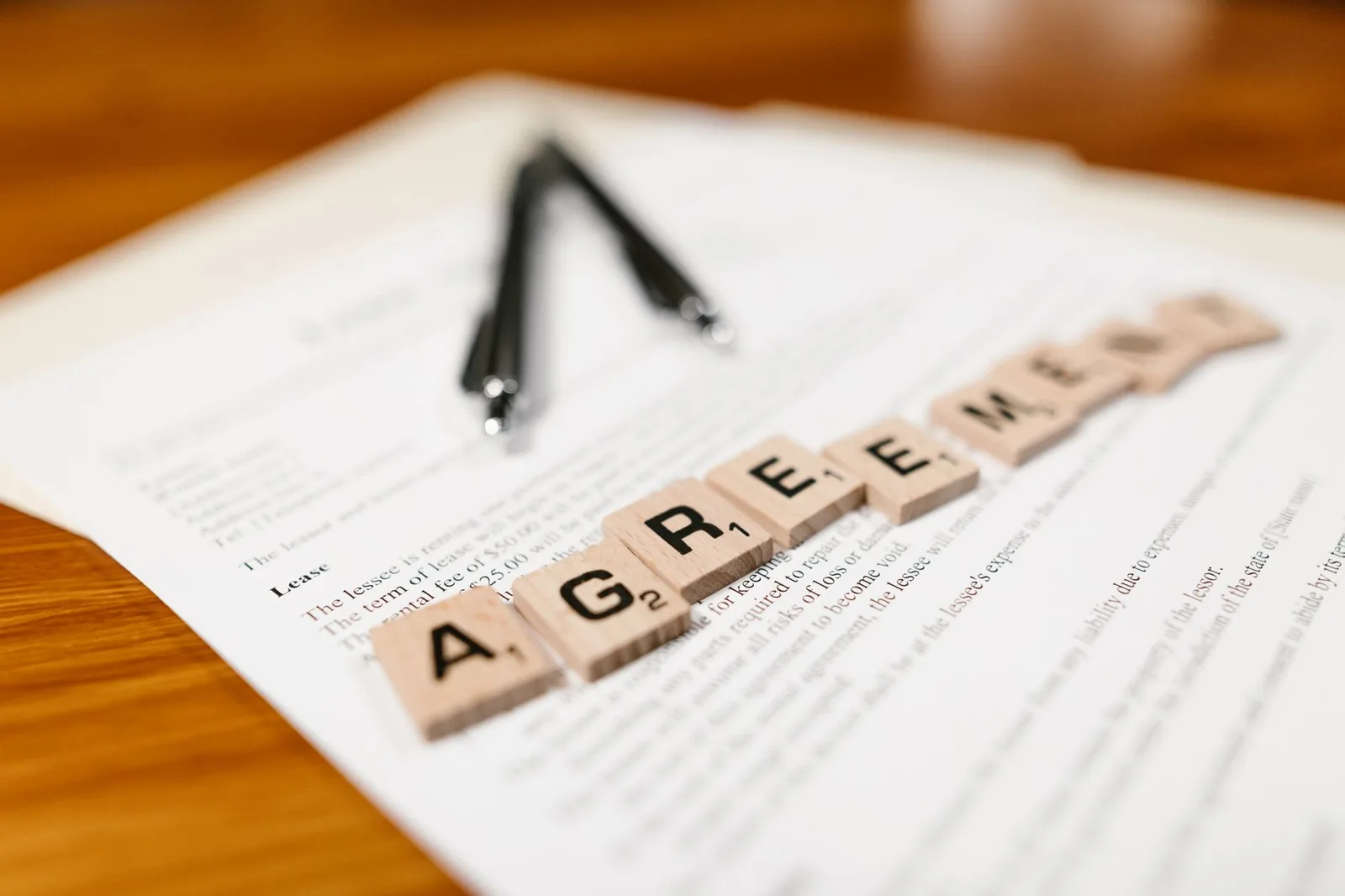 Lettres formant le mot accord posées sur un document contractuel avec un stylo