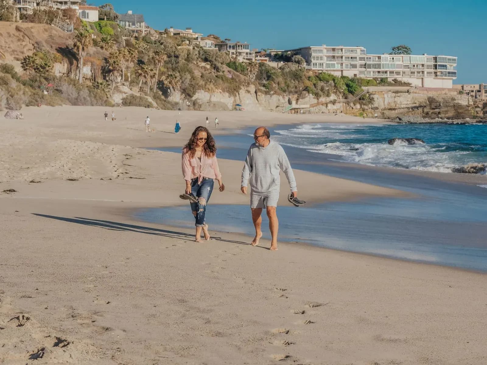 Couple de retraités se promenant sur une plage ensoleillée au bord de la mer