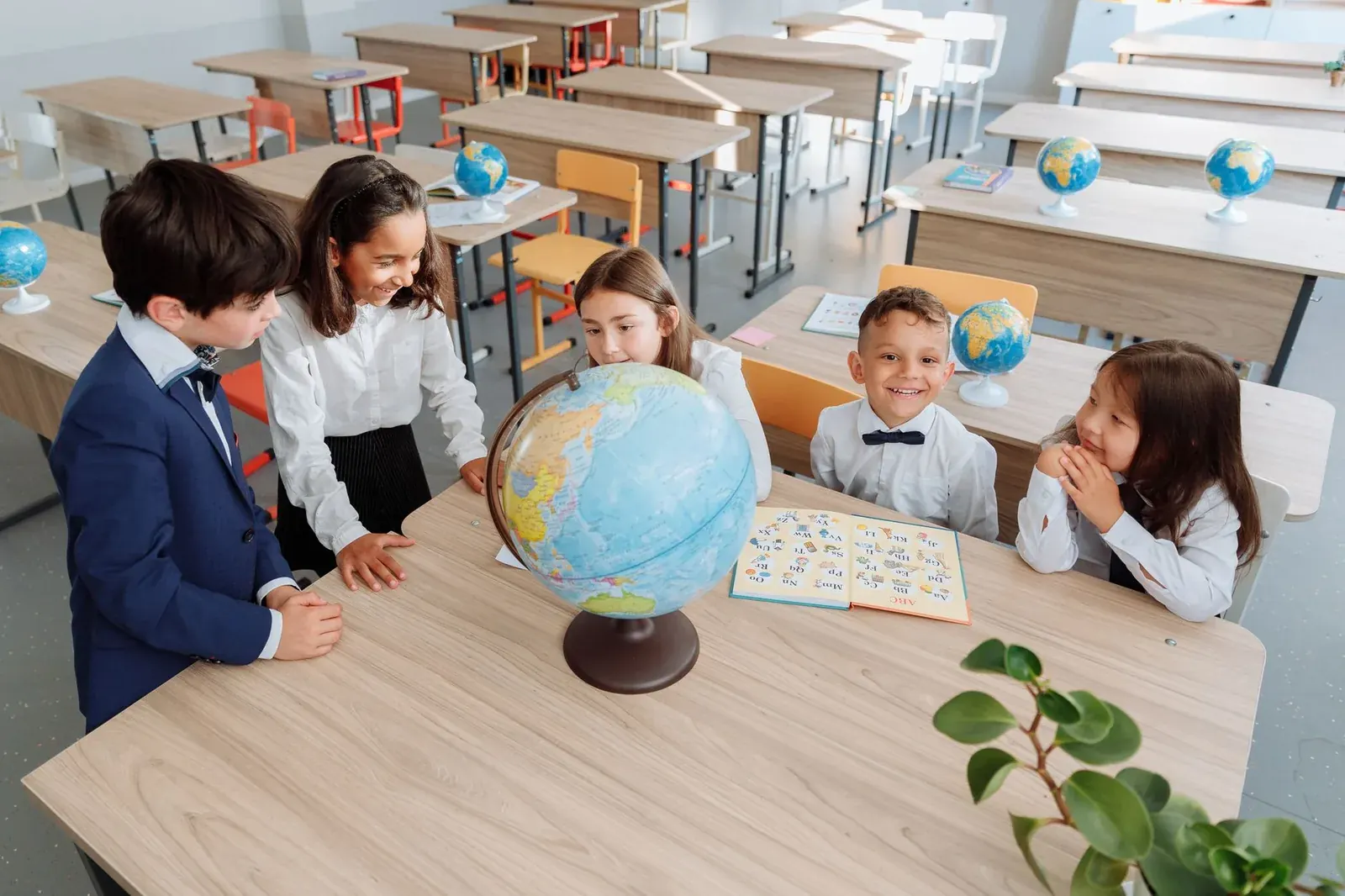 Enfants en uniforme autour d'un globe dans une salle de classe internationale