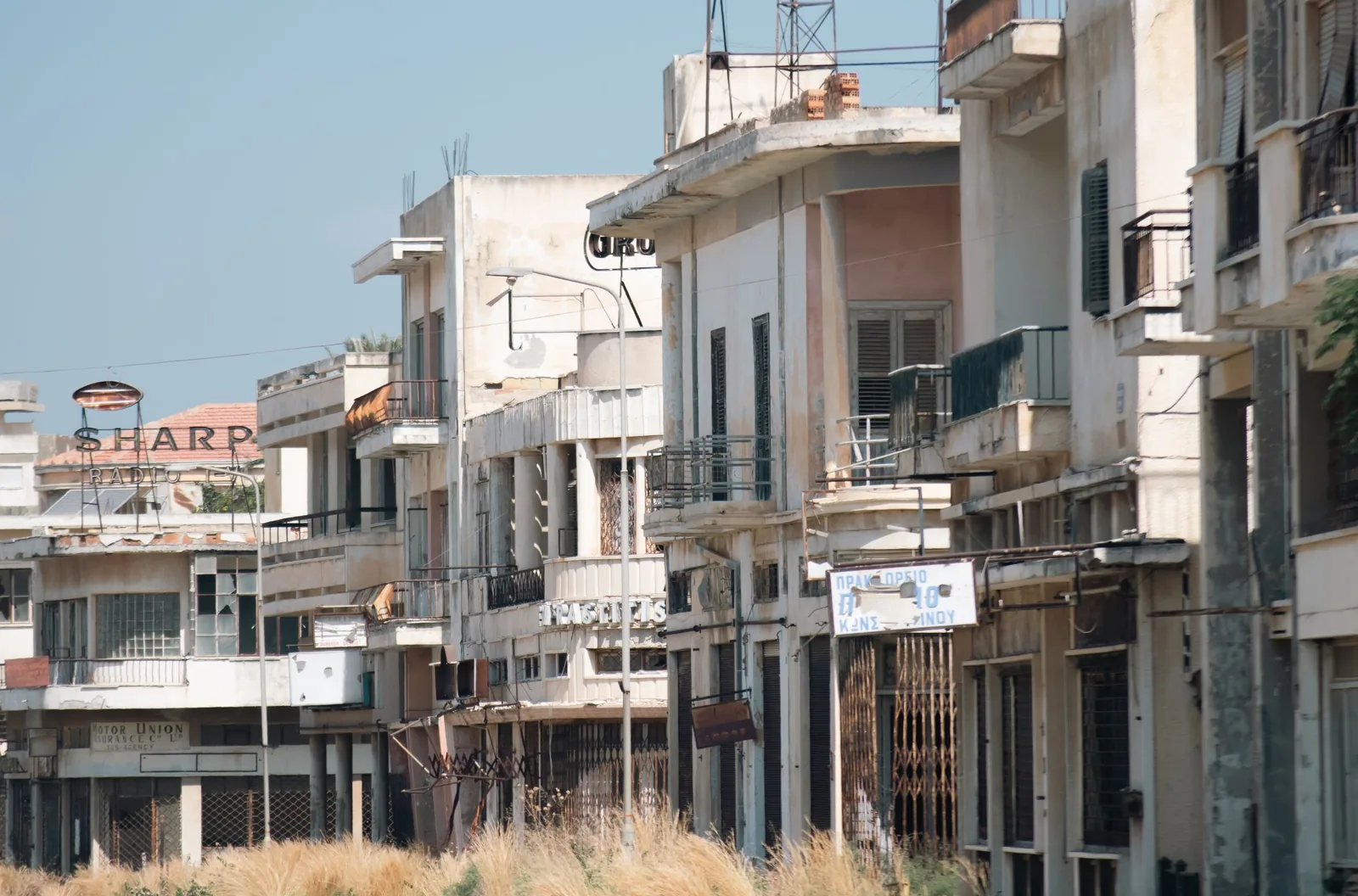 Rue de Varosha bordée d'immeubles et de commerces abandonnés aux enseignes anciennes, à Famagouste